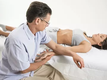 Til Luchau works on a supine client's wrist.