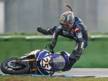 A motorcycle racer lays the bike over too far and is in midair after jumping off it.