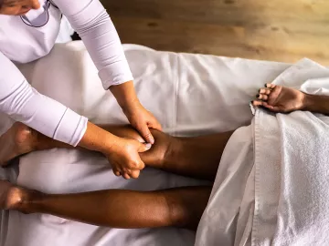 A massage therapist works on a client's calf.