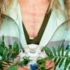 A woman with a scar on her chest holds a plant.