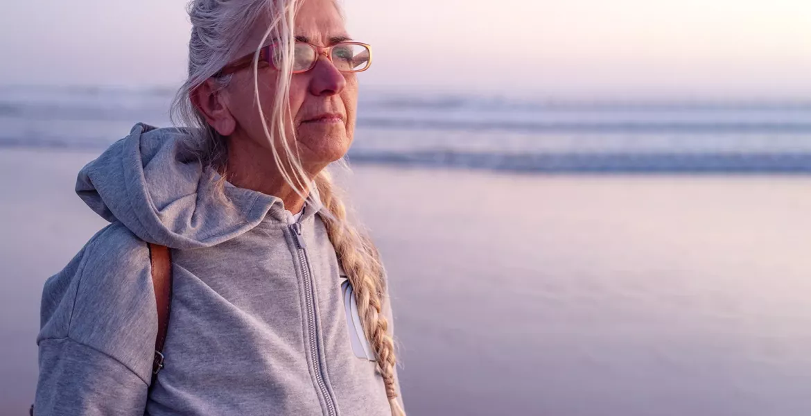 An elderly lady looks out across an ocean.