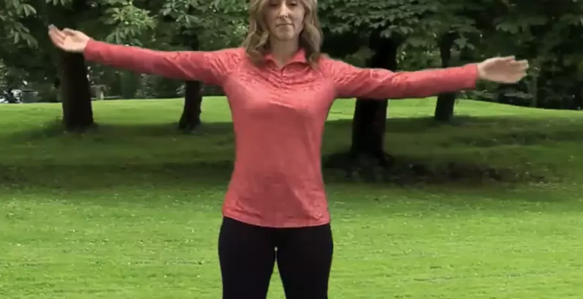 author Angie Parris stands outside on the grass, stretching with her legs and arms outstretched.
