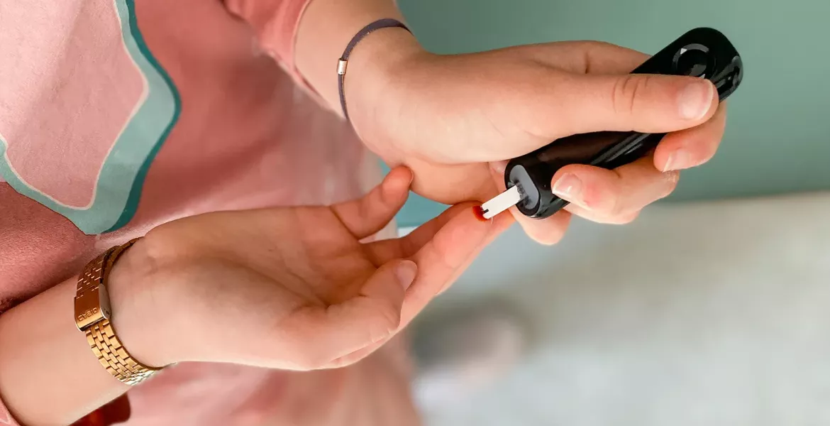 A person self-administers a blood test to their finger.