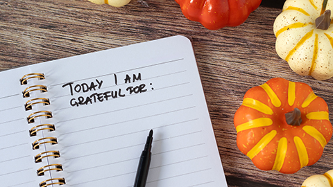 handwritten text in notebook with pumpkins on wooden background.
