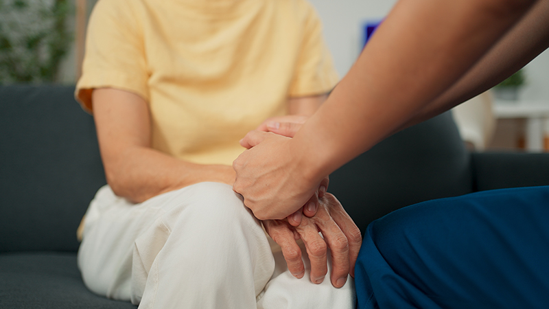 Young caregiver nurse providing care and supporting senior woman at home visit.