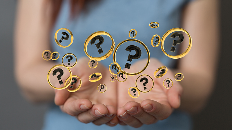 A female holding question mark bubbles.
