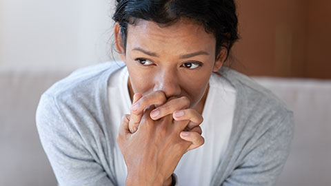 Woman with hands clenched near face, looking anxious