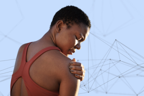 A woman grabs her right shoulder in pain.