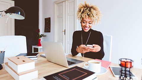 A woman using her phone and tablet for marketing her business.