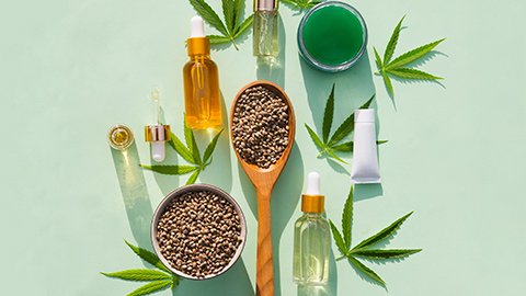 CBD oils and hemp seeds lay flat against a light blue background.