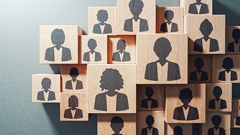 Wooden blocks etched with images of employees cast in a shadow.