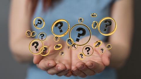 A female holding question mark bubbles.